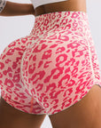 Pink leopard print shorts worn by a person on a light gray background